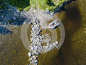 Aerial view of a fishing motor boat in the lake. Beautiful summer landscape with ships. Clear water with sandy and stone beach at