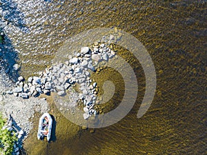 Aerial view of a fishing motor boat in the lake. Beautiful summer landscape with ships. Clear water with sandy and stone beach at