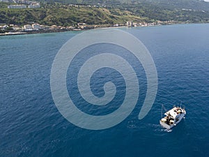 Aerial view of a fishing vessel in the blue sea off the coast of Calabria, Italy