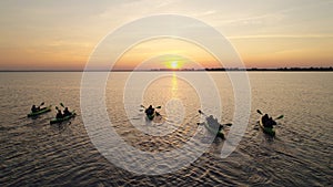 Aerial view of five kayaks with tourists. They sail to meet the sunrise.