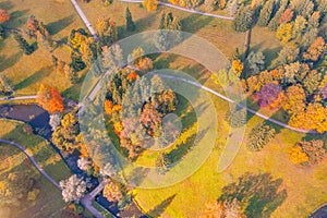 Aerial view flight over autumn valley park with meadows and a winding river with bridge, bright trees