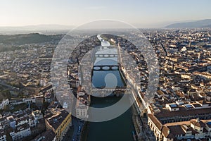 Aerial view of Florence skyline along Arno river at sunset with Ponte Vecchio bridge in foreground, Florence, Tuscany, Italy