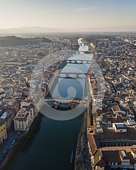 Aerial view of Florence skyline along Arno river at sunset with Ponte Vecchio bridge in foreground, Florence, Tuscany, Italy