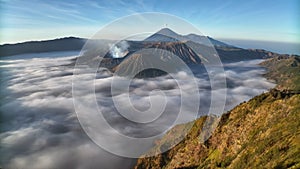 Aerial view fly back over the sea of mist to reveal Bromo volcano, Indonesia
