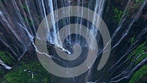 Aerial view fly over trees and tilt to reveal Tumpak Sewu waterfall, Indonesia