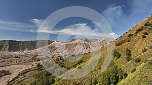 Aerial view fly pass hill to reveal Bromo volcano in a background, Indonesia