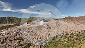 Aerial view fly pass hill to reveal Bromo volcano in a background, Indonesia