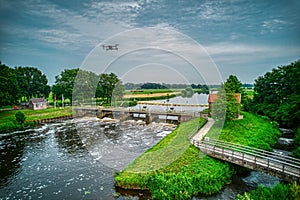 An aerial view with a flying drone in the background above a weir in the river Vecht. Lock keepers house next to the bridge. Fish photo