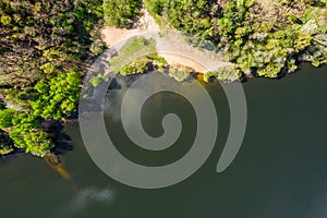 Aerial view from flying drone of lakeside with clouds reflection and green forest