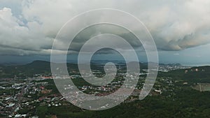Aerial view flying over city Dark clouds storm moves in over Phuket city Thailand
