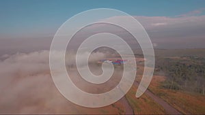 Aerial view, flying through and over the fog at sunset, countryside with a road