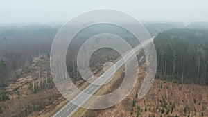 Aerial view of flying over the highway with traffic in the fog, forest landscape