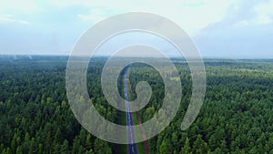 Aerial view flying over road. Green forest. Drone shot from above.
