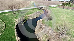Aerial view flyover Illinois farmland in early spring with creek and open fields