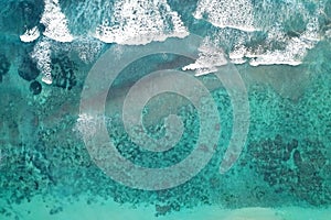 Aerial view of foaming waves crashing on sandy beach