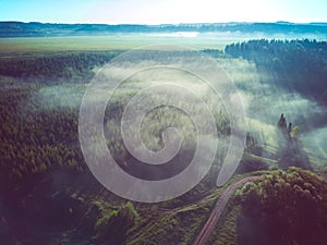 Aerial view of foggy countryside landscape with road and forest