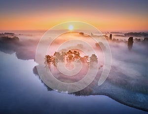 Aerial view of foggy forest at colorful sunrise in autumn