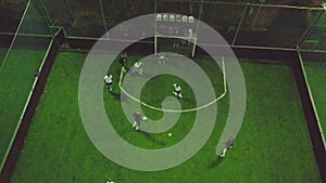 Aerial view of football pitch at night with amateur football players playing the game in the city. Clip. Top view of the