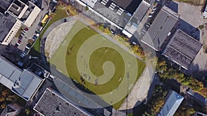 Aerial view of football stadium with a small number of players. City centre.