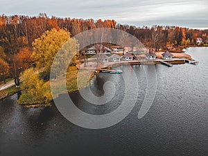 Aerial view of forest and blue lake. Sauna house by the lake shore. Wooden pier with fishing boats. St. Petersburg, Russia