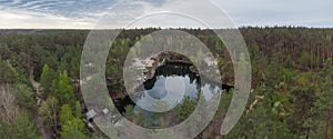 Aerial view of forest lake with rocky shores in overcast