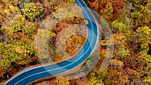 Aerial view of forest road in beautiful autumn . Serpentines details with colourful landscape with no traffic and yellow trees