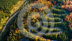 Aerial view of forest road in beautiful autumn .at sunset. Mountain roads details with colourful landscape with heavy traffic and
