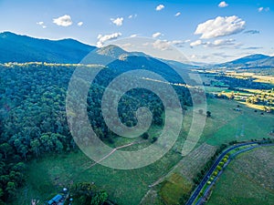 Aerial view of forested mountains, meadows, pastures, and rural road.