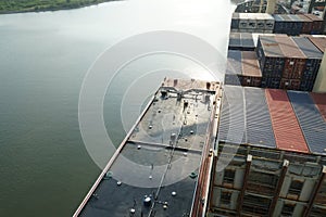 Aerial view on forward part of bunker barge with valves and manifolds alongside of the container vessel.