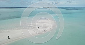 Aerial view of four people walking along sandy coast