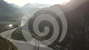 Aerial view of freeway interstate road in italian alps with fast moving traffic and rural green landscape.