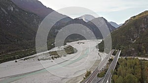 Aerial view of freeway interstate road in italian alps with fast moving traffic and rural green landscape.