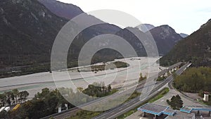 Aerial view of freeway interstate road in italian alps with fast moving traffic and rural green landscape.