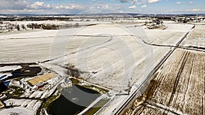 Aerial View Of A Frosty Landscape Featuring A Pond, Railroad, And Snowy Fields.