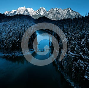 Aerial view of  frozen Eibsee river surrounded by trees covered with snow in Bavaria, Germany
