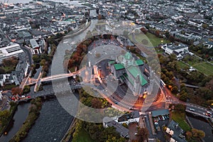 Aerial view on Galway Cathedral Building illuminated by city lights at dusk. Salmon Weir Bridge and new pedestrian bridge. Dark