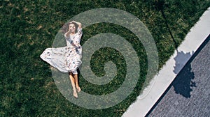 Aerial View of The Girl that Lies on a Green Lawn in a White Dress