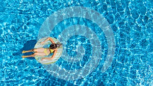 Aerial view of girl in swimming pool from above, kid swim on inflatable ring donut, fun in water on family vacation