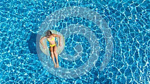 Aerial view of girl in swimming pool from above, kid swim on inflatable ring donut and has fun in water