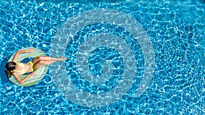 Aerial view of girl in swimming pool from above, kid swim on inflatable ring donut in water on family vacation