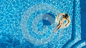 Aerial view of girl in swimming pool from above, kid swim on inflatable ring donut in water on family vacation