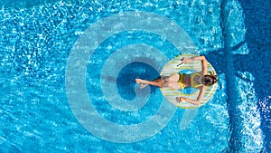 Aerial view of girl in swimming pool from above, kid swim on inflatable ring donut in water on family vacation