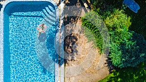 Aerial view of girl in swimming pool from above, kid swim on inflatable ring donut in water on family vacation