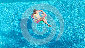 Aerial view of girl in swimming pool from above, kid swim on inflatable ring donut in water on family vacation