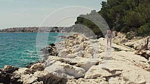 Aerial view girl walks on the rocks and lies down in the sea