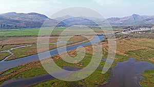 Aerial view of the Glaslyn Marshes close to the railway with the Snowdonia mountain range national park in background -