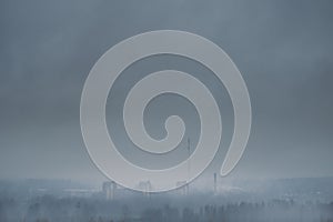 Aerial view of a gloomy city in the forest. Thick fog