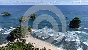 Aerial view of Goa Cina beach with white sand and big waves in Indonesia