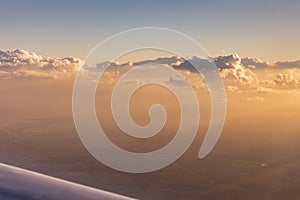 Aerial view of golden clouds lit by the evening sun over Florida, view from the aircraft during the flight.