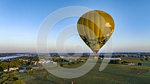 Aerial View of a Golden Hot Air Balloon, Floating Across Fields of Corn, in rural America
